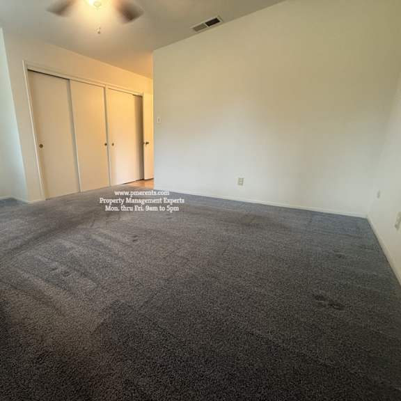 a room with grey carpet and two doors.