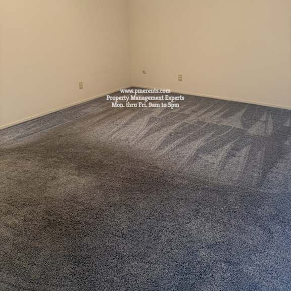 a room with a carpeted floor and a ceiling fan.