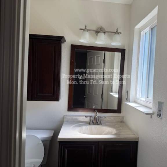 a bathroom with a sink, mirror, and toilet.