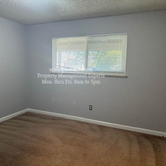 a room with a carpeted floor and a window with blinds.