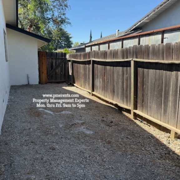 a backyard with a wooden fence and a gravel ground.
