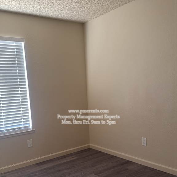 a room with wooden flooring and a window with blinds.