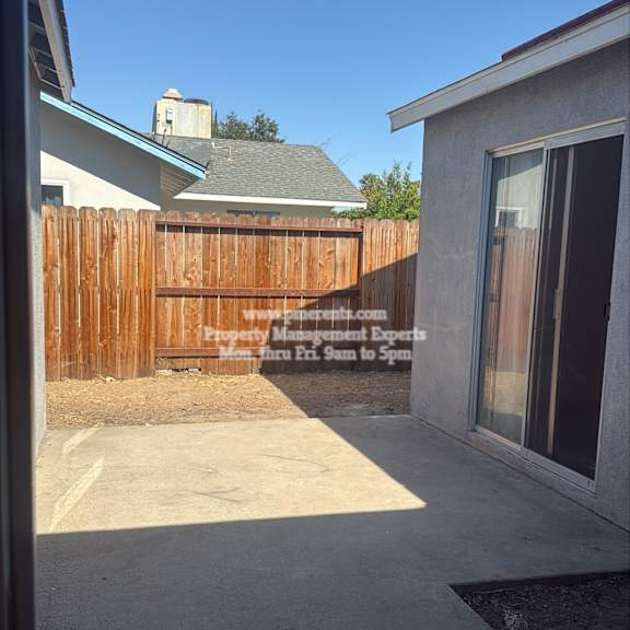 a backyard with a wooden fence and a house in the background.