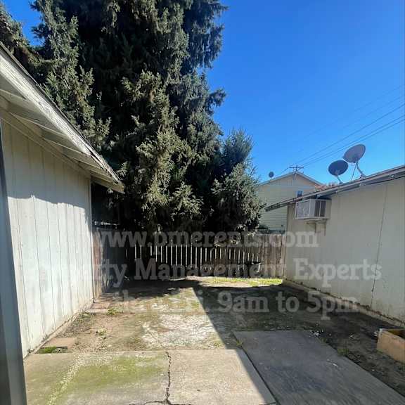 a backyard with a concrete patio and a white fence.