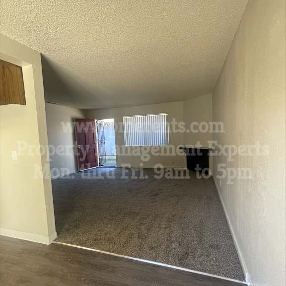 a room with a carpeted floor and a window with blinds.