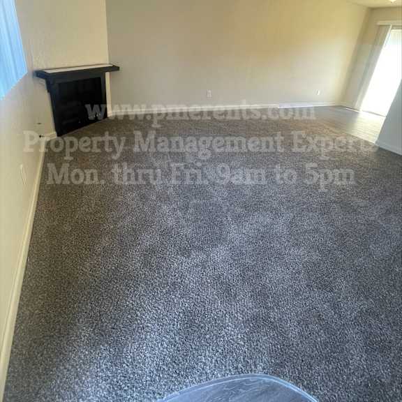 a room with a grey floor and a white wall with a black shelf on it.
