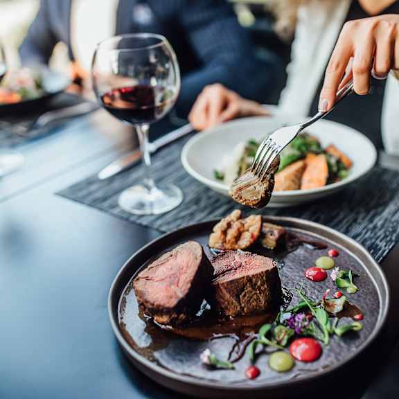A person is eating a meal with a glass of wine on the table.