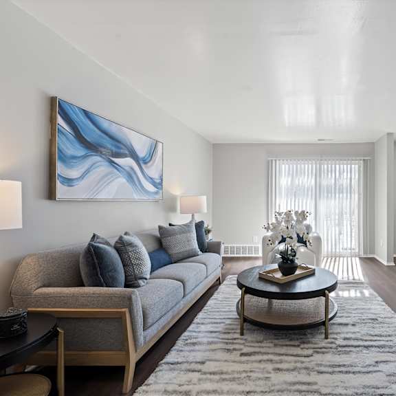 a living room with a grey couch, a coffee table, and a painting on the wall.