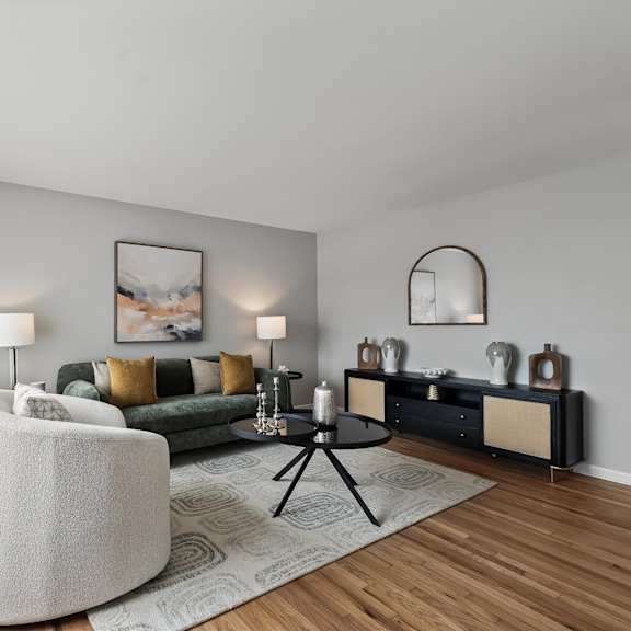 a modern living room with a white sofa, a green couch, and a large painting on the wall.