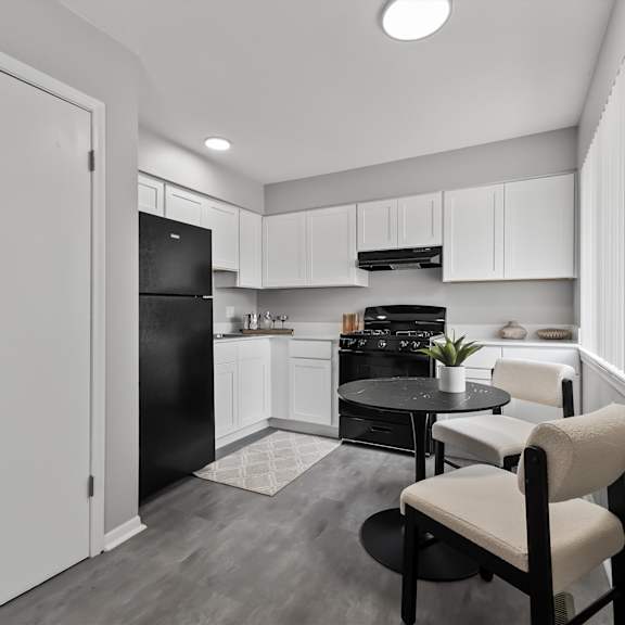 a black and white photo of a kitchen with a table and chairs.