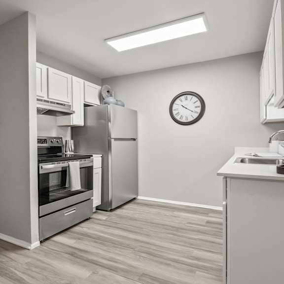 a modern kitchen with a stainless steel refrigerator and a wooden floor.