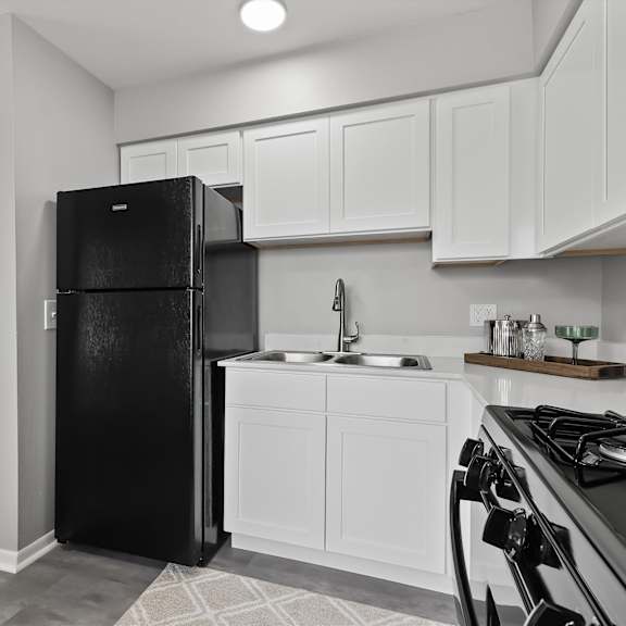 a black refrigerator in a kitchen with white cabinets.