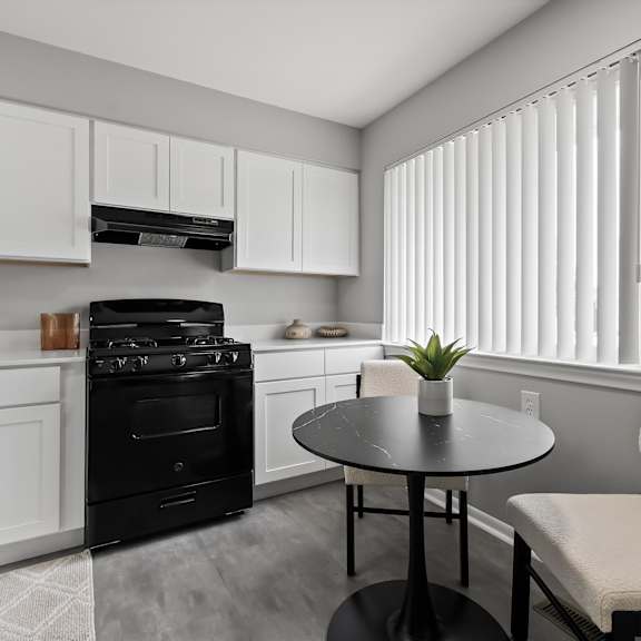 a black oven sits in a kitchen with white cabinets and a round table.