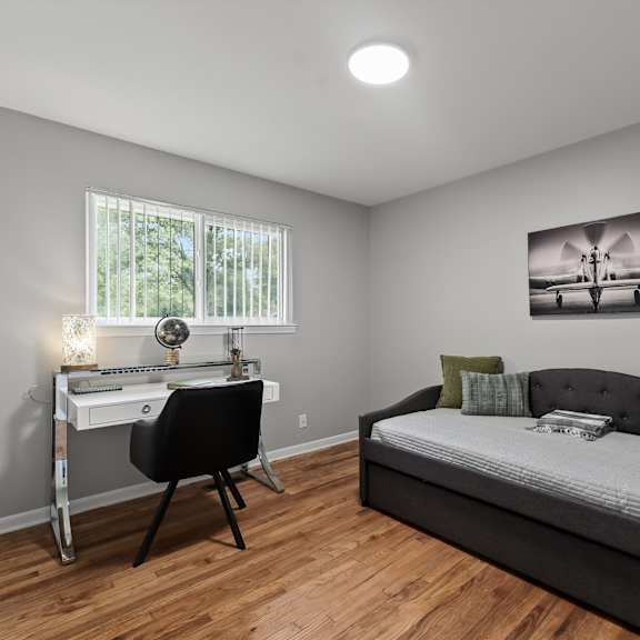 a bedroom with a bed, desk, and chair.