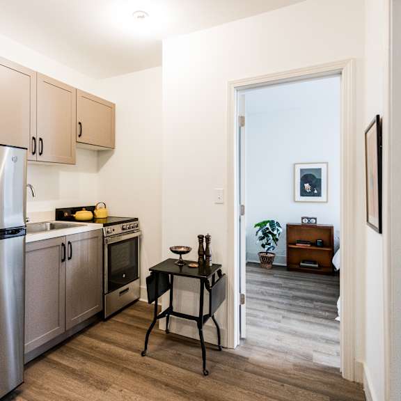 a kitchen with a refrigerator, oven, and a table.