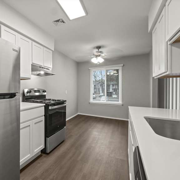 a modern kitchen with a stainless steel refrigerator and wooden flooring.