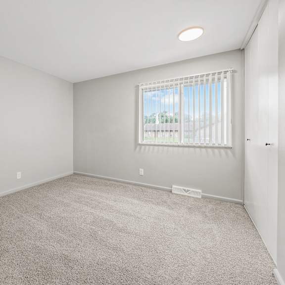 a bedroom with a large window and a carpeted floor