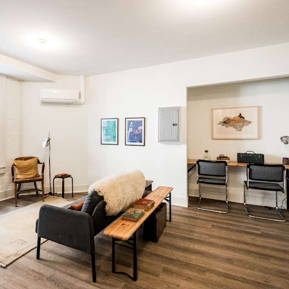 a living room with a couch, chairs, and pictures on the wall.
