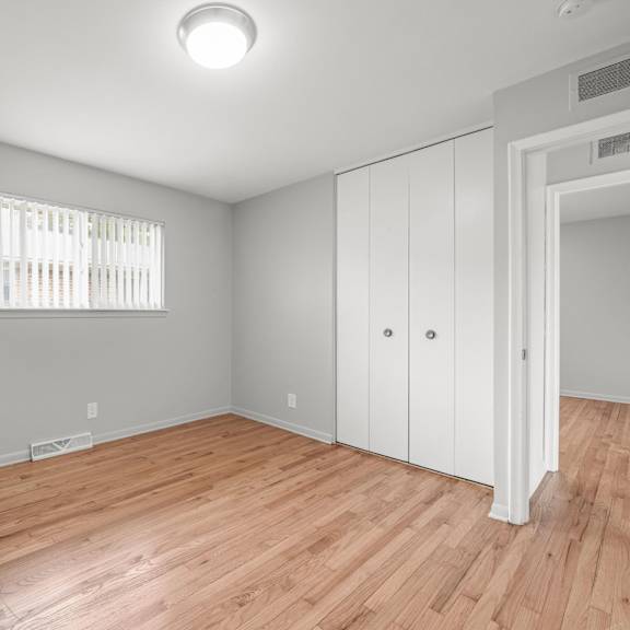 a bedroom with hardwood floors and grey walls