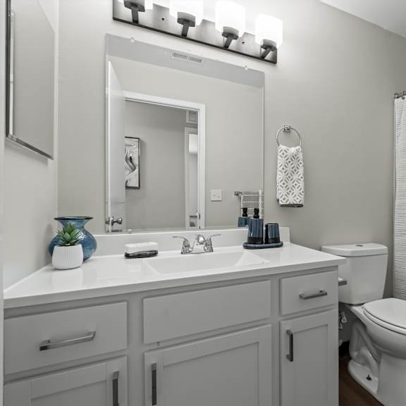 a white bathroom with a toilet, sink, and shower curtain.