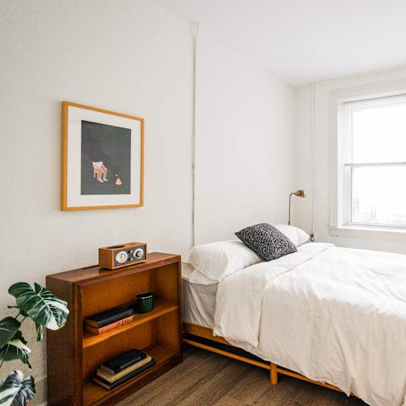 a bedroom with a bed, nightstand, and a window.