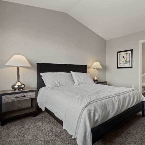 a bedroom with a bed, nightstand, and lamp.