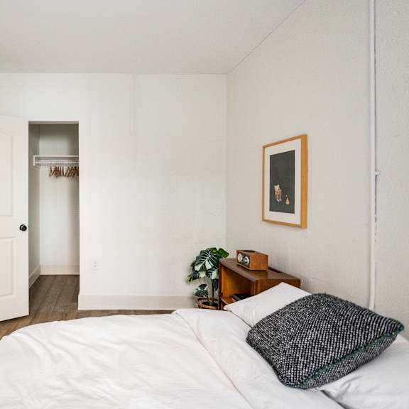 a bedroom with a white bed and a picture frame on the wall.