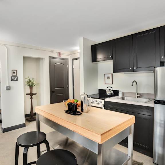 a kitchen with a wooden table and black stools.