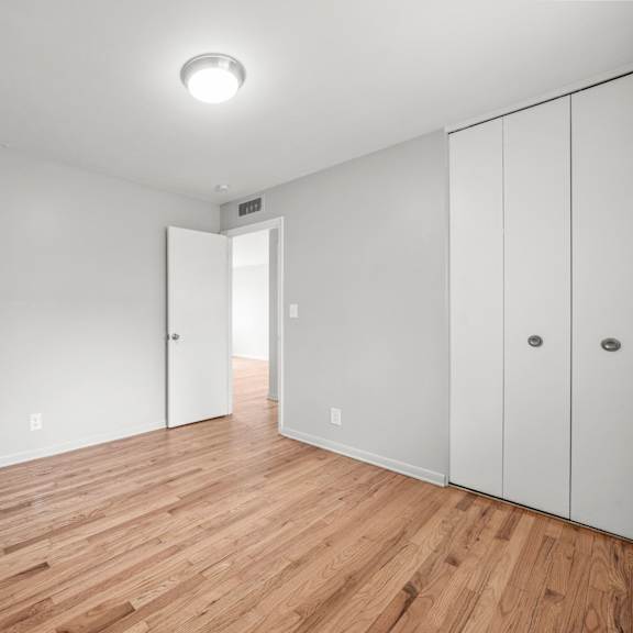 a bedroom with white walls and hardwood floors