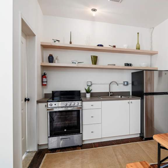 a kitchen with a stove, oven, refrigerator, and a wooden table.