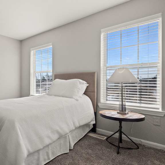 second bedroom with a twin bed and a small table with a lamp on it.