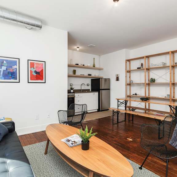 a living room with a black leather couch, a wooden coffee table, and a chair.