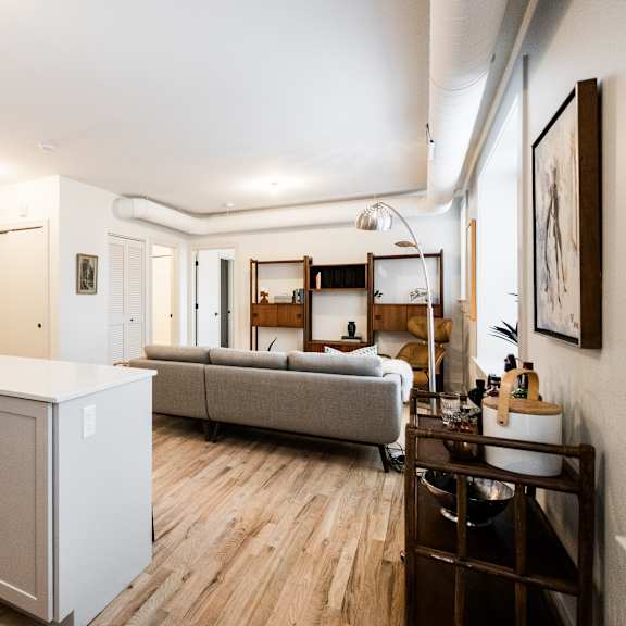 a living room with a grey couch and wooden floors.
