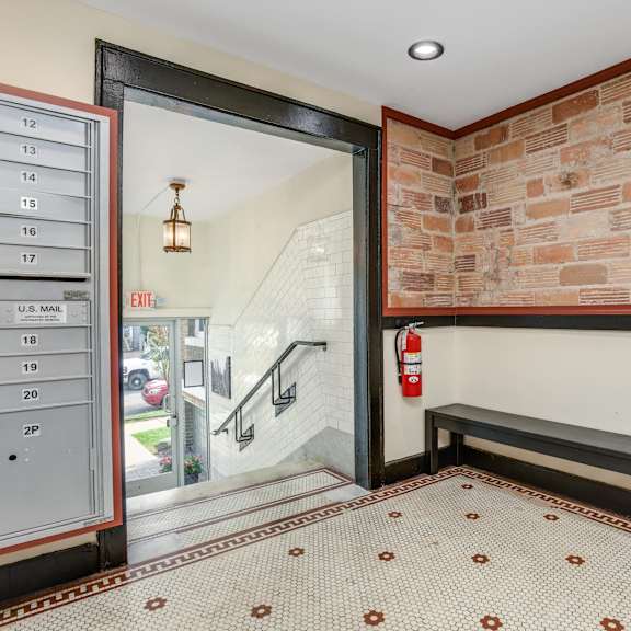 the entrance to a building with a brick wall and a mail room with a bench