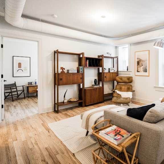 a living room with a grey couch, a wooden coffee table, and a large window.