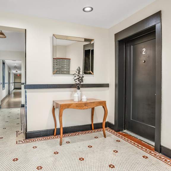 a hallway with a table and a black door     and a mirror
