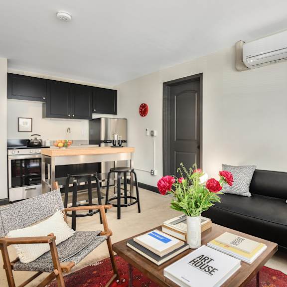 a black couch sits in a living room with a coffee table in front of it.