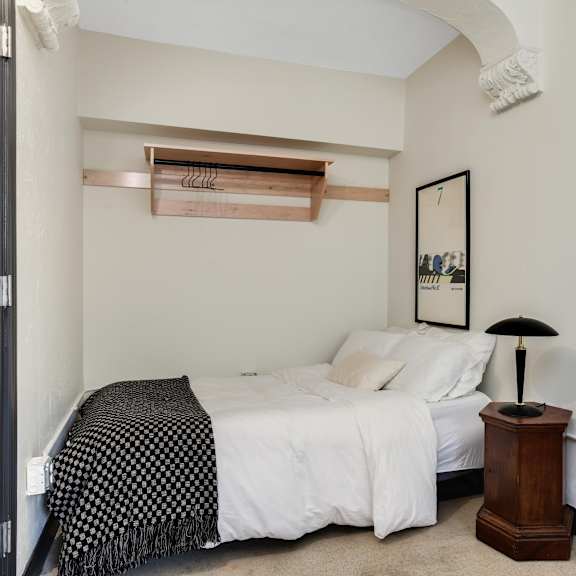 a bedroom with a bed, a lamp, and a picture on the wall.