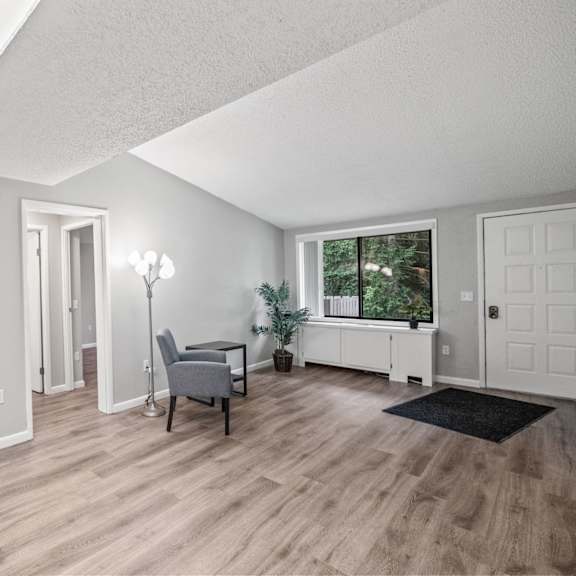 a room with a wooden floor and a window with a view of trees.