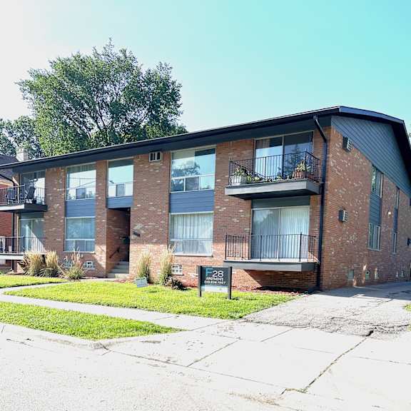 a brick apartment building with a sidewalk in front of it