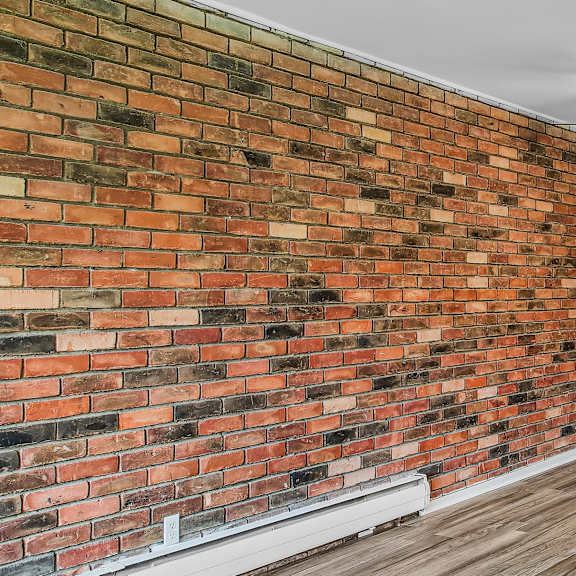a room with a brick wall and a ceiling fan.