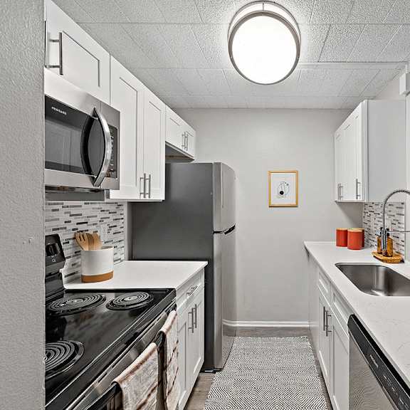 a kitchen with white cabinets and a black stove top oven.