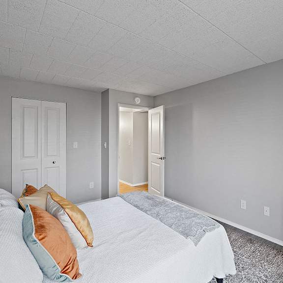 a bedroom with a bed, pillows, and a chair.