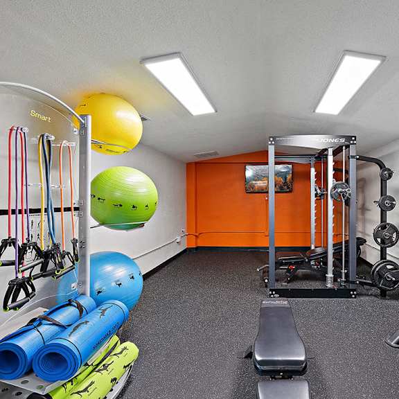 a gym with a variety of equipment including a bench, weights, and resistance bands.