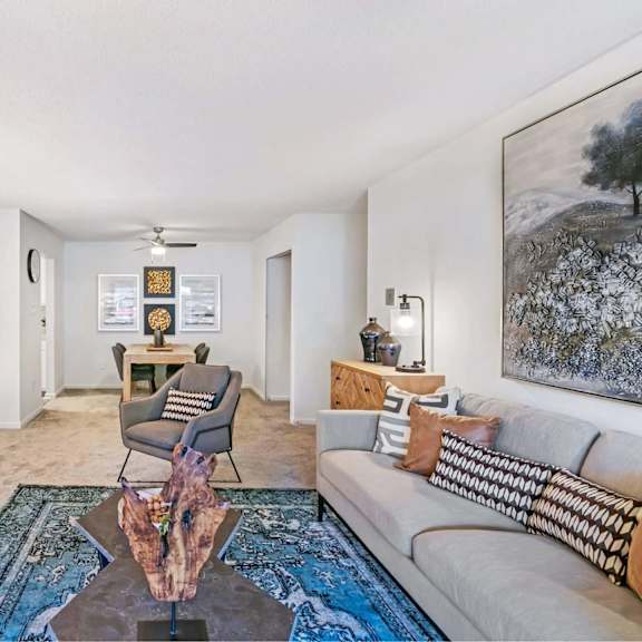 a living room with a grey couch, a coffee table, and a painting on the wall.