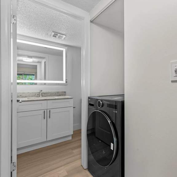 a washing machine is placed in a room with a white wall and a door leading to another room.