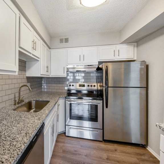 a kitchen with a stainless steel refrigerator, oven, and sink.