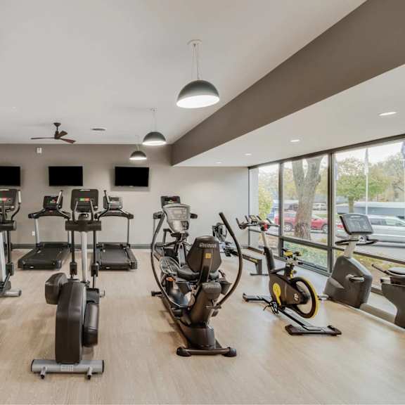 a gym with a variety of exercise equipment including treadmills, stationary bikes, and elliptical machines.