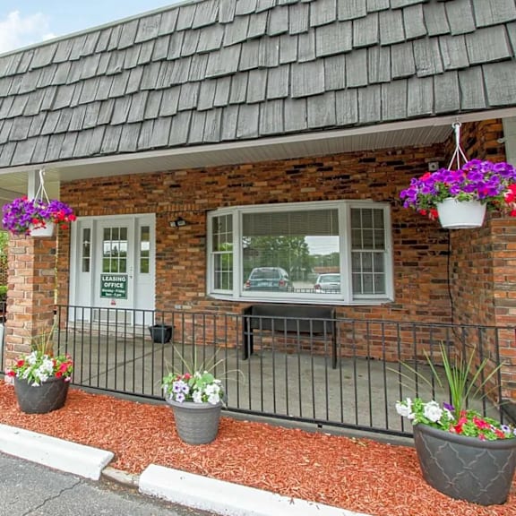 the front of a brick building with a porch and flowers in pots