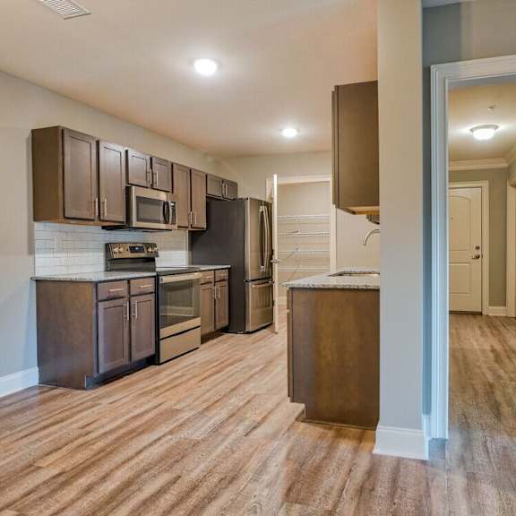 Thumbnail 4 of 5 A kitchen with brown cabinets and a wooden floor at Mode at Melbourne, LLC Apartments, Florida, 32901